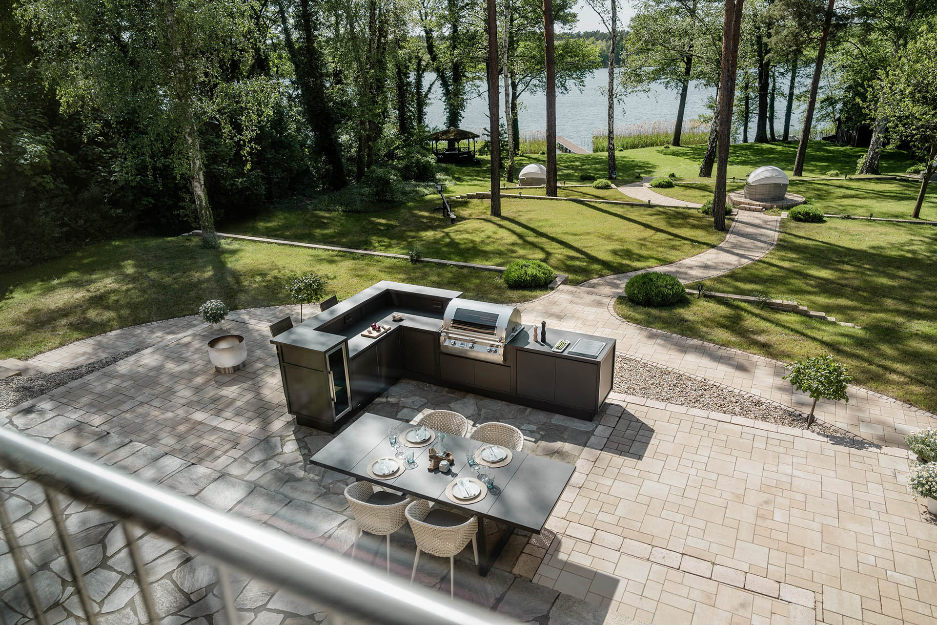 Großzügige BURN Outdoorküche in U-Form mit integriertem Grill auf eleganter Gartenterrasse direkt am Seeufer.