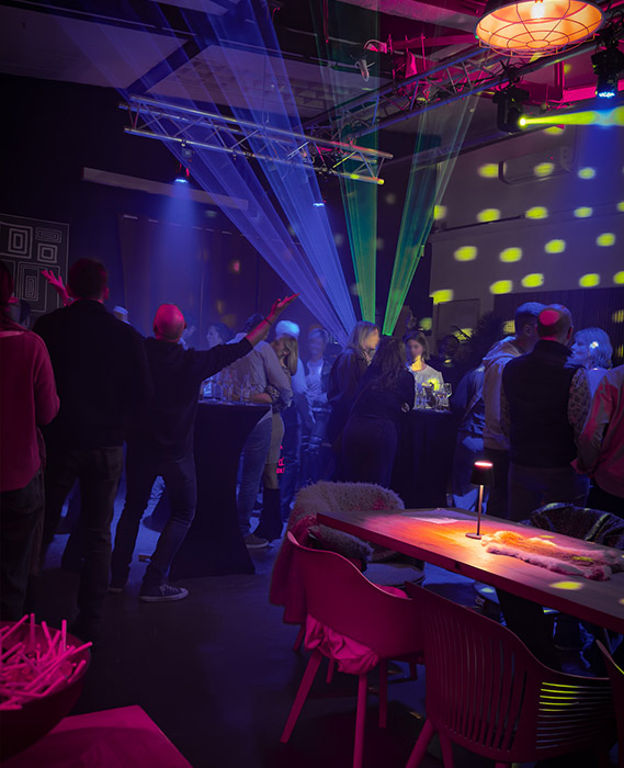 Besucher auf einer Afterwork-Party in unserer Eventlocation mit DJ-Musik, Lichtshow und entspannter Networking-Atmosphäre zwischen Stehtischen und Lounge-Bereich