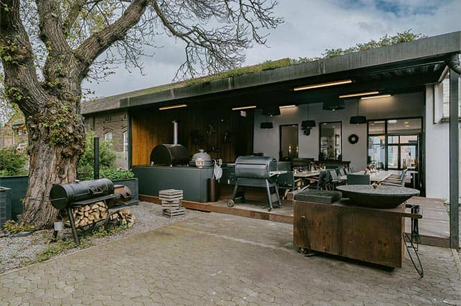 Perfekt für Familienfeiern in Düsseldorf: überdachte Terrasse mit Outdoorküche und freier Bereich mit Baum und verschiedenen Grillmöglichkeiten