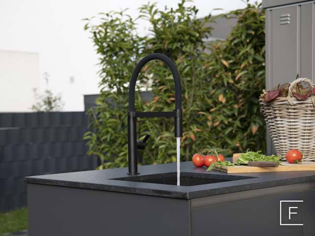 Wasser läuft aus schwarzer Küchenarmatur einer Outdoorküche