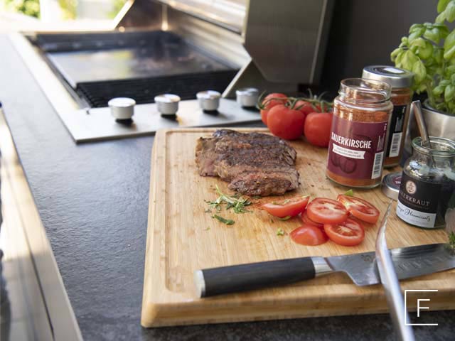 Auf einem Küchenbrett liegen Grillfleisch und verschiedene Gewürze